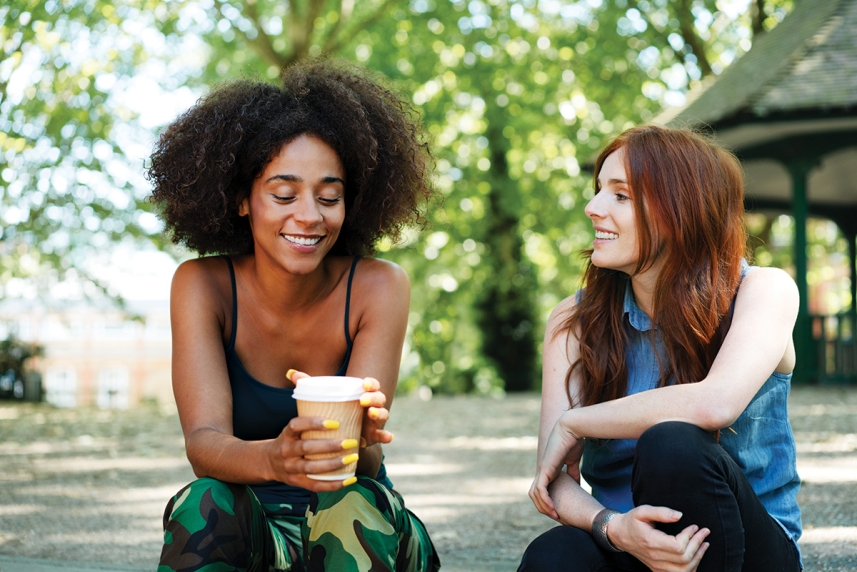  Dos mujeres sentadas. Uno toma una taza de café.