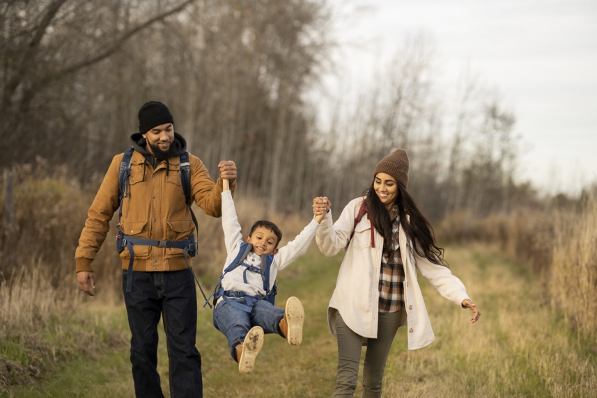 A man and woman hiking in a field with a child