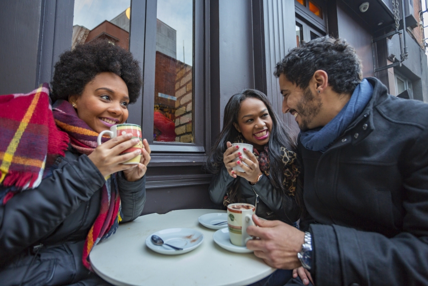 Un grupo de amigos con ropa de invierno sentados en una mesa y tomando café.
