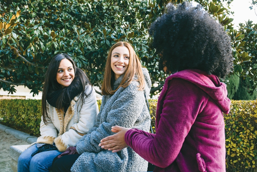 Tres adultos sentadas en un banco.