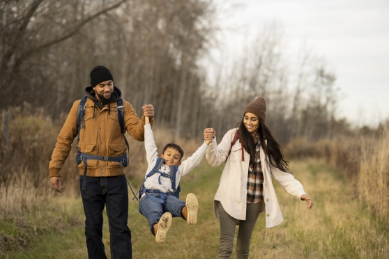 A man and woman hiking in a field with a child